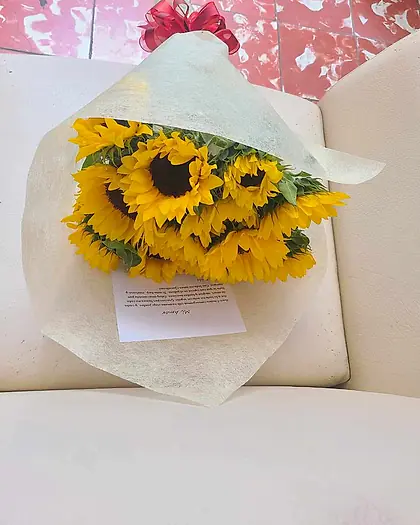 Ramo de girasoles envuelto en papel blanco sobre un sofá