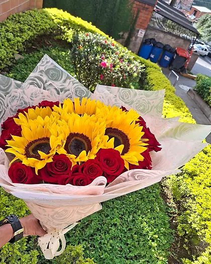 Ramo grande de girasoles y rosas rojas envuelto en papel blanco