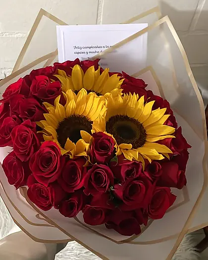 Ramo de rosas rojas con dos girasoles al centro y envoltura blanca